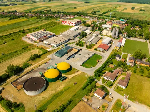 Aerial view of a biogas plant with green digester domes beside farmland