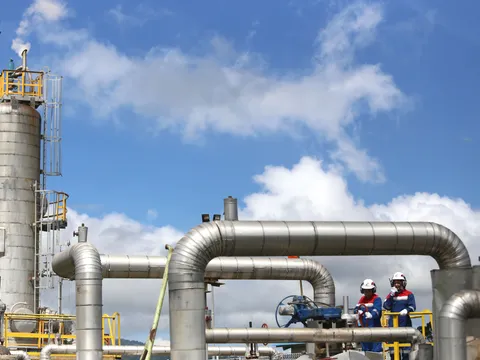 Workers in hard hats among process plant pipework