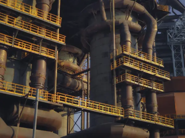 An engineer in a hard hat and hi-vis jacket working on red plant pipework