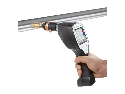 A handheld dew point meter connected to a sampling point on a compressed air pipe