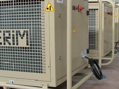 A row of beige tent air conditioners with protective frames lined up in a hall